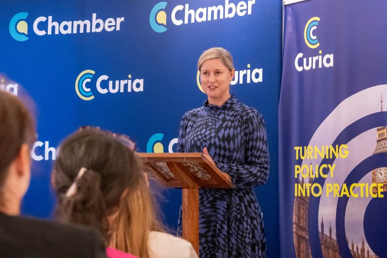 Chief Executive of NICE , Dr Sam Roberts, speaking in front of a Curia and Chamber UK Banner