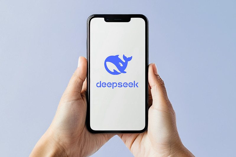 Hands holding a smartphone with the logo if DeepSeek AI
