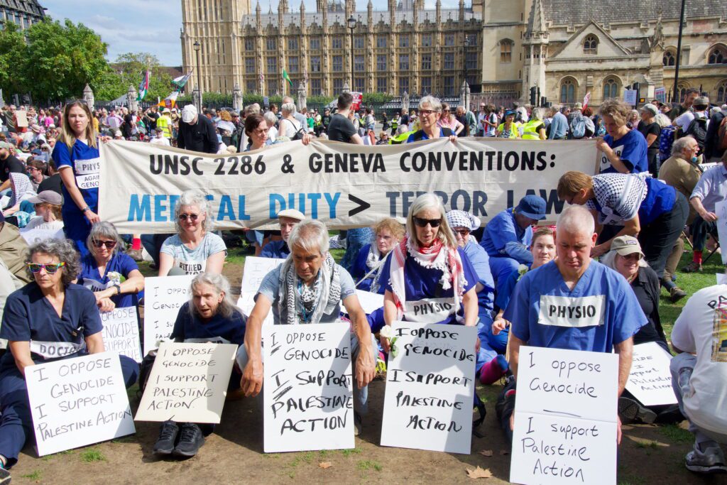 Palestine Action protestors holding signs showing their support for the organisation.